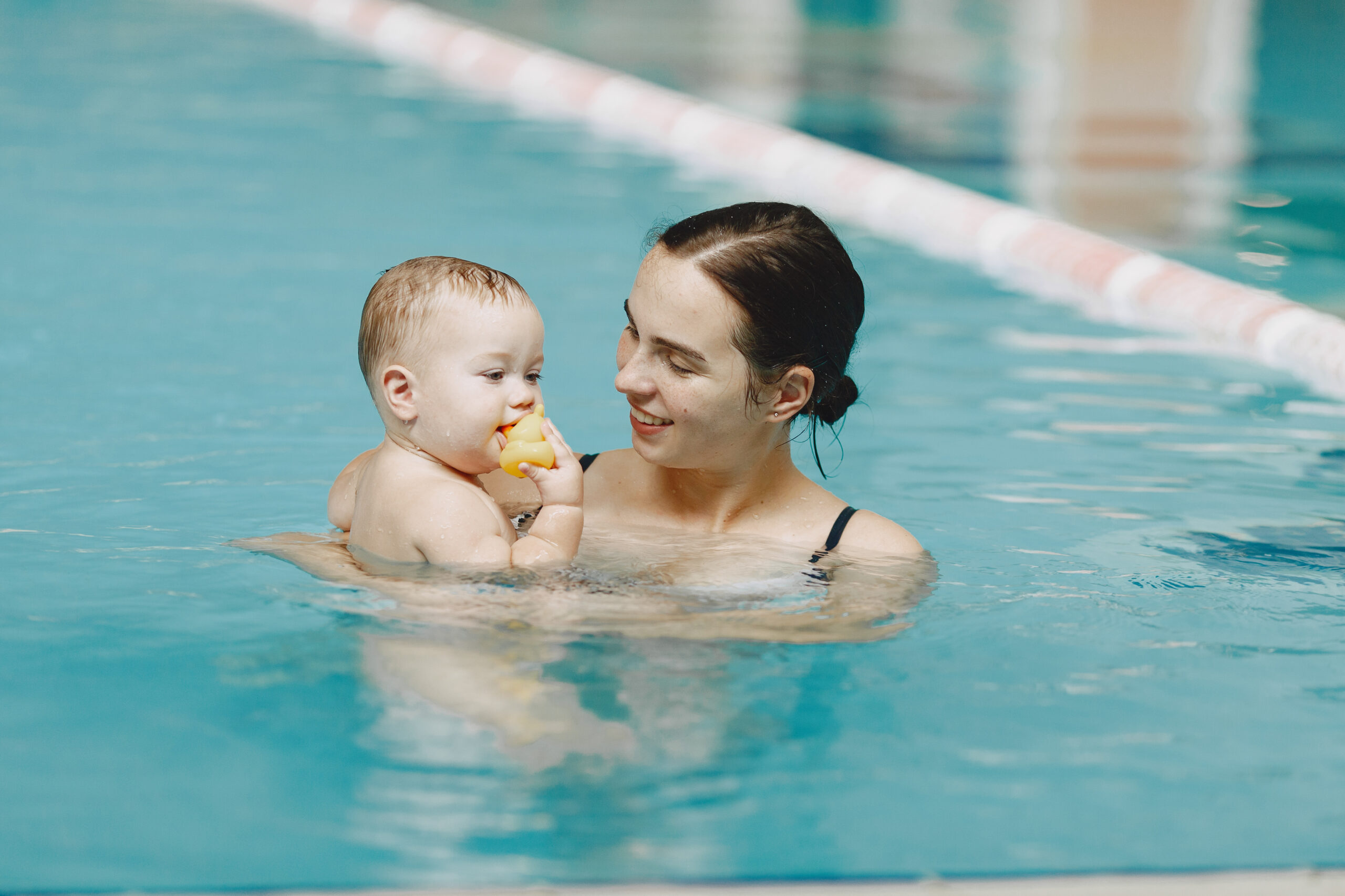 Mother and little son enjoying swimming in a swimming pool